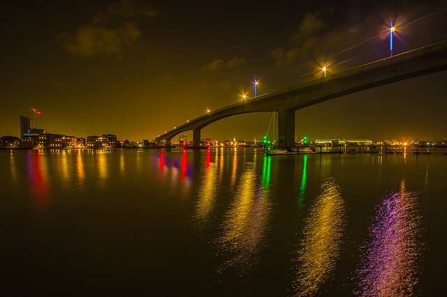image of a bridge with coloured over water at night time